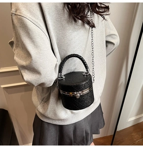 Close-up of mini black sequined bucket bag with quilted texture and silver metal clasp