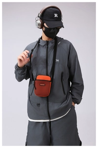 Detail of vibrant orange waterproof phone bag with black mesh pocket and strap worn by model
