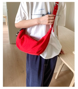 Detail shot of a red nylon crescent moon bag featuring a wide adjustable shoulder strap