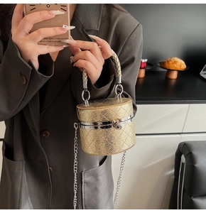 Nahaufnahme der goldenen gesteppten Zylindertasche mit geflochtenem Griff und Silberkette