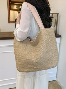 Minimalist woven straw tote bag with pink fabric straps shown on shoulder of a model