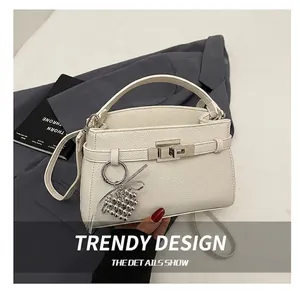 Detail of white lychee leather handbag with silver lock and heart bead charm accessory