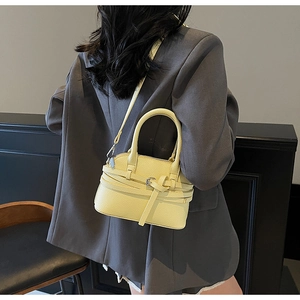 Détail d'un sac coquille jaune clair en cuir grainé avec boucle décorative et bandoulière