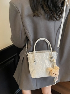 Borsa a secchiello plissettata argento con orsetto indossata da modella in tailleur