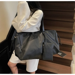 Détail du grand sac cabas noir tissé avec pochette zippée assortie sur escalier