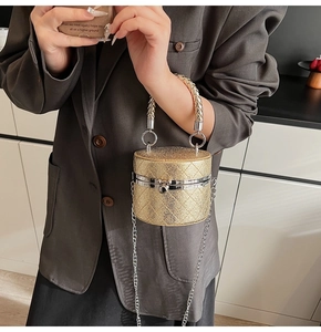 Details einer goldenen Mini-Eimertasche mit Rautensteppung und gewebtem Metallgriff