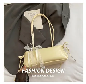 Detail of cream leather shoulder bag featuring white lace bows and side ribbon drawstrings