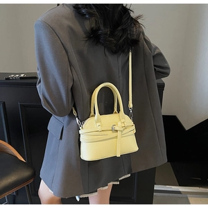 Détail du sac à main jaune en forme de coquille avec cuir grainé et boucles dorées