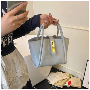 Detail of light blue crocodile embossed leather bucket bag with gold metal buckle