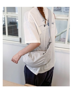 Detail view of large grey crescent crossbody bag showing nylon texture and wide strap
