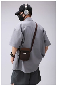 Detail view of mini brown crossbody bag with mesh pocket and textile shoulder strap