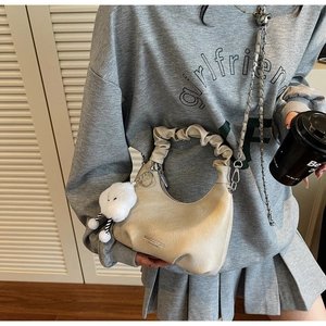 Détail du sac à main crème avec breloque nuage en peluche et bandoulière en chaîne métal