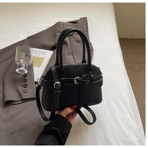 Détail du sac coquille en cuir noir grainé avec sangle et fermeture éclair