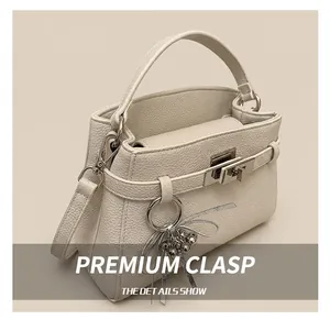 Macro shot of silver metal rotating hook and lychee leather detail on the cream Kelly bag