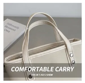 Detail shot of off-white handbag with double handles, metal zippers and silver rivets