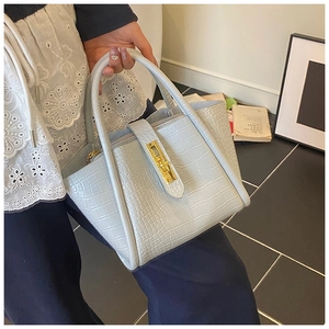 Detail of light blue croc-embossed bucket bag with elegant gold hardware and turn-lock