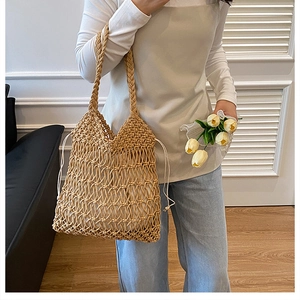 Detail of hollow woven cotton straw beach bag with drawstring closure and braided handle