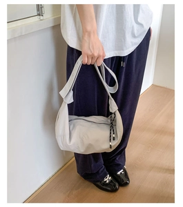 Close-up of light grey nylon crescent bag featuring a woven rope zipper detail