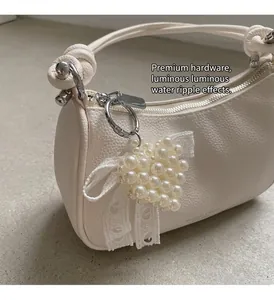 Dettaglio della borsa a luna bianca in pelle martellata con ciondolo a cuore di perle
