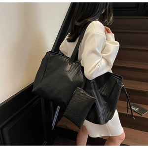 Détail de la texture d'un sac cabas noir tressé avec sa petite pochette zippée assortie