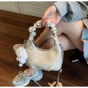 Détail du sac crème à poignée plissée avec texture gaufrée et breloque nuage