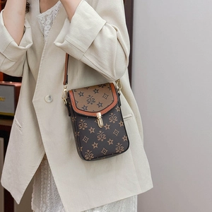 Detail of a mini monogrammed crossbody bag with gold buckle and brown leather strap