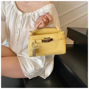 Detail of yellow lychee grain handbag featuring metal turn-lock and bow charm