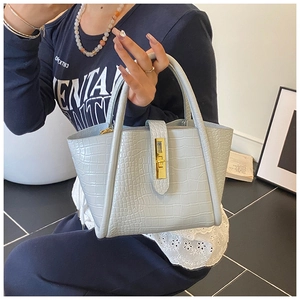 Detailed close-up of light blue crocodile embossed leather texture and gold twist lock