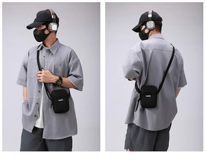Front and back view of a black nylon crossbody phone bag with adjustable strap and logo