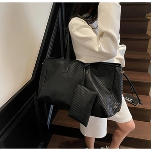 Détail du sac cabas tressé noir avec pochette assortie et longues anses d'épaule
