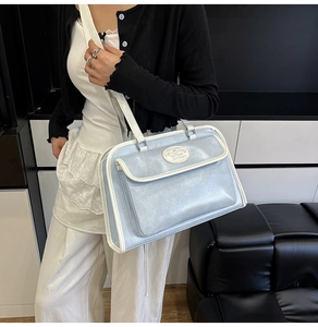 Détail du cabas en cuir miroir bleu clair avec passepoil blanc et poche avant magnétique