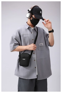 Detail of a minimalist black crossbody phone bag styled with a casual techwear outfit