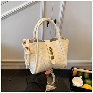 Detail of cream faux crocodile bucket bag with golden metal clasp and adjustable strap