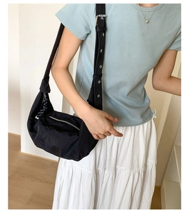 Detail of black nylon crescent bag with adjustable eyelet shoulder strap and metal buckle