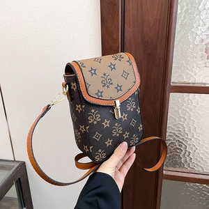 Detail of vintage star-patterned crossbody phone bag with gold clasp and brown strap