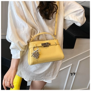 Close-up of yellow pebble leather trapezoid bag with silver twist lock and heart charm