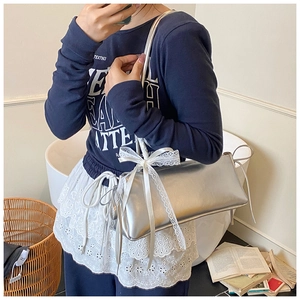 Chic silver shoulder bag with white lace bow detail shown in an indoor lifestyle scene