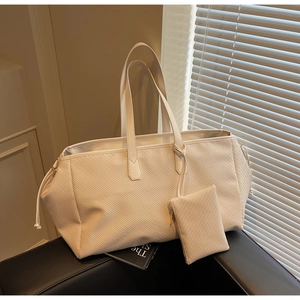 Gros plan détaillé de la texture tissée du sac cabas crème avec petite pochette zippée
