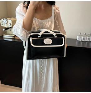 Détail d'un sac cabas vintage noir et blanc en cuir avec un badge logo circulaire unique