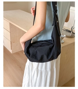 Detail of black nylon crescent bag featuring wide strap with silver metal eyelets