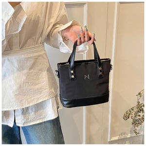 Detail of black nylon bucket bag with leather bottom and silver metal logo lettering