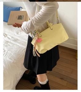 Chic creamy yellow bucket bag with heart charm shown in a cozy indoor lifestyle setting