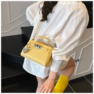 Detailed view of yellow leather kelly style handbag with silver turn-lock and crystal charm