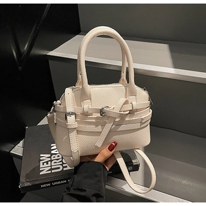Détail d'un sac à main blanc crème avec motif litchi, boucle décorative et bandoulière