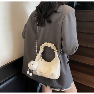 Détail du sac plissé crème avec inscription de la marque et pendentif nuage en peluche
