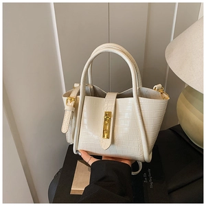 Detail of creamy white faux crocodile skin bag with elegant vertical gold lock buckle