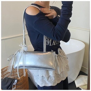 Detail of silver metallic shoulder bag featuring white lace ribbon bows and dual straps
