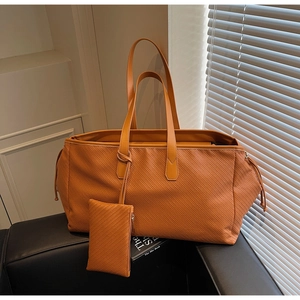 Vue détaillée du sac cabas en cuir tressé avec pochette assortie sur fauteuil