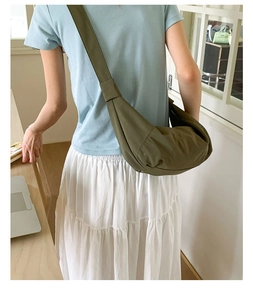 Rear view of a model wearing a green nylon crescent bag with wide shoulder straps