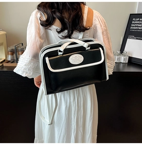 Détail du sac à bandoulière contrasté noir et blanc avec écusson ovale rétro